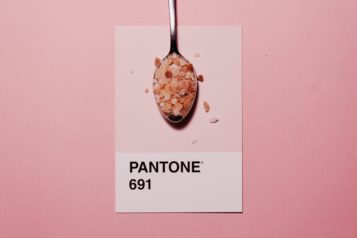 A spoon holding pink salts over a Pantone swatch numbered 691